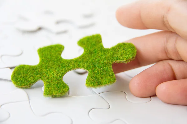 Mão segurando uma peça de puzzle verde — Fotografia de Stock