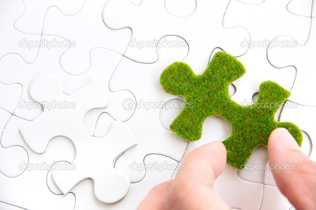 Hand holding a green puzzle piece