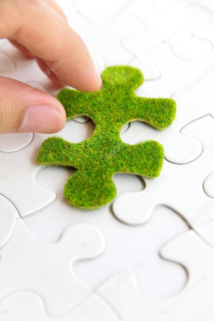 Hand holding a green puzzle piece