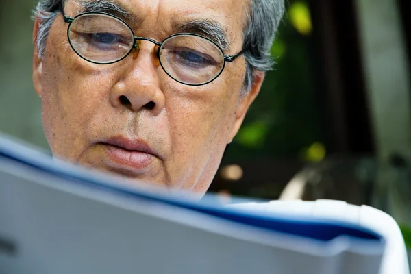 Hombre mayor leyendo E-book en su tableta . — Foto de Stock