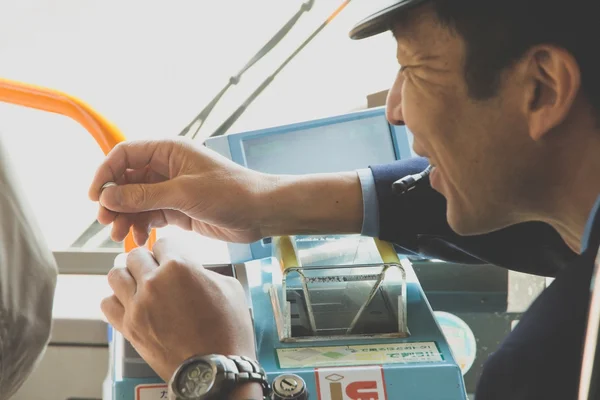 Japanischer Linienbusfahrer gibt einem Fahrgast das Wechselgeld — Stockfoto