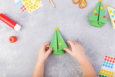 Çocuklar kağıt ağacı origamisini süsler. Noel kâğıdı kolajı. Kendi elleriyle yapmış. Çocuklar için sanat projeleri. Çocuklar için el işi. Üst görünüm