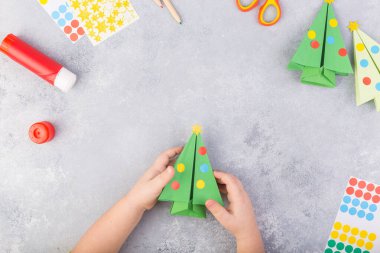 Çocuk kağıt ağacı origamisini süslüyor. Noel kâğıdı kolajı. Kendi elleriyle yapmış. Çocuklar için sanat projeleri. Çocuklar için el işi. Üst görünüm
