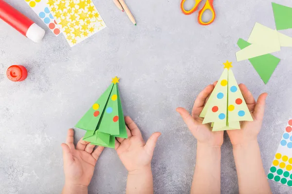 I bambini decorano origami di albero di carta. Collage di carta natalizia. Realizzato con le sue mani. Progetto artistico per bambini artigianale per bambini. Artigianato per bambini. Vista dall'alto — Foto Stock