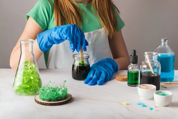 Linda chica en gafas de química impresionado por el crecimiento de cristal verde. La ciencia es un concepto divertido con los niños en casa — Foto de Stock