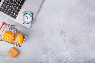 Mavi masada dizüstü bilgisayar ve turuncu hediyeler. Tatil çevrimiçi alışveriş kavramı.