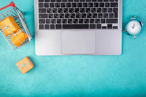 Portátil y naranja presenta en la mesa azul plana laico. Vacaciones concepto de compras en línea. —  Fotos de Stock