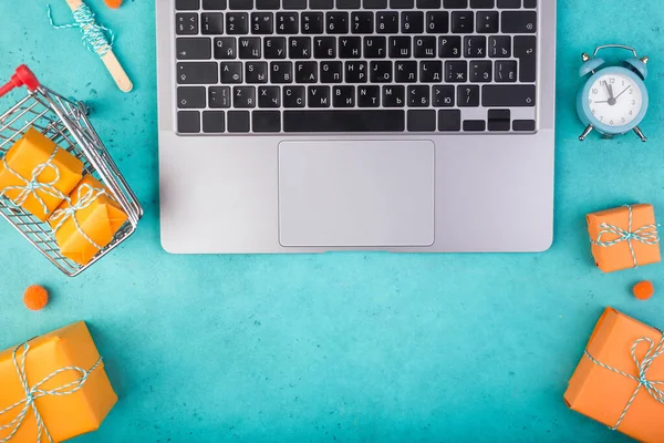 Laptop και πορτοκαλί δώρα σε μπλε τραπέζι επίπεδη lay. Online διακοπές έννοια ψώνια. — Φωτογραφία Αρχείου