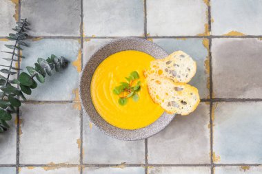 Beyaz fayanslı balkabağı ve havuç kremalı çorba ve kızarmış ekmek. Üst görünüm.