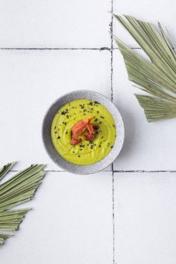 Fayans palmiye yapraklarında ızgara pastırmalı yeşil çorba püresi.