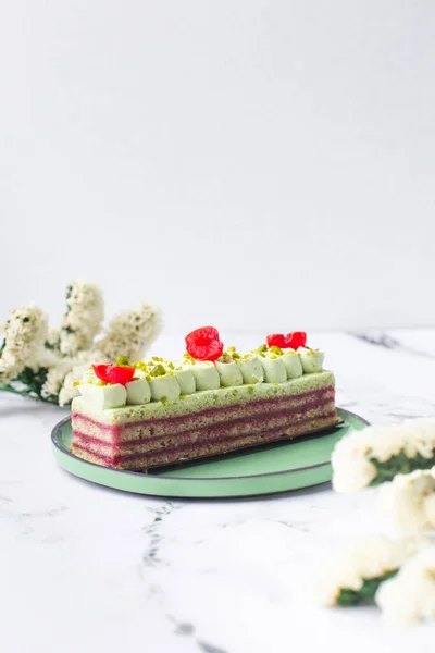 Pastel de postre decorado con crema verde, cereza y pistacho sobre fondo de mármol — Foto de Stock