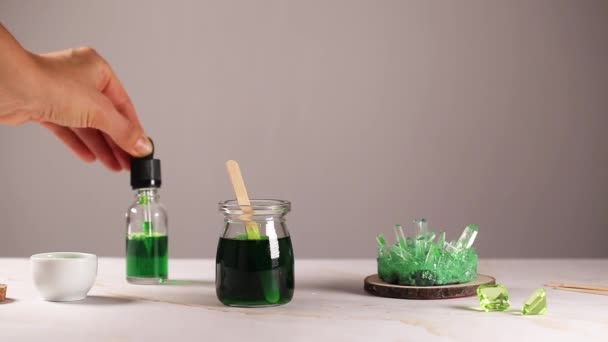 Vihreä kristalli kasvanut prosessi, nainen käsi tippaa vihreää ainetta lasipurkissa. Tiede on hauska käsite. Lasten kokeilu kotona. — kuvapankkivideo