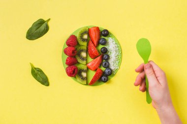 Smoothie kasesi taze böğürtlen ve meyveli kağıt tabakta sarı çocuk eli sağlıklı yiyecek kavramı.