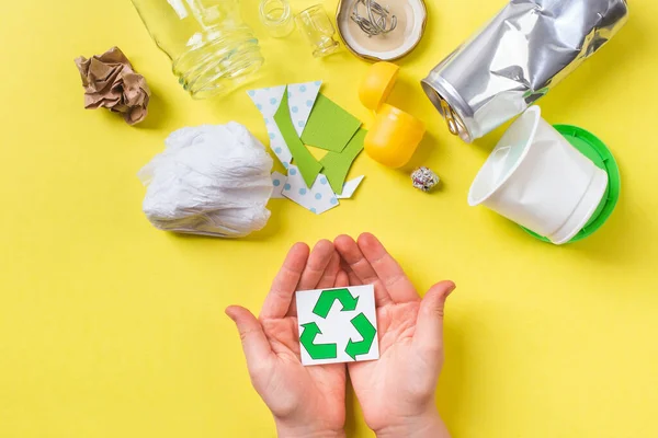 Çocuk ellerinde geri dönüşüm tabelası, temiz çöp metali, plastik kağıt ve cam. Sarı üzerinde geri dönüşüm kavramı. — Stok fotoğraf