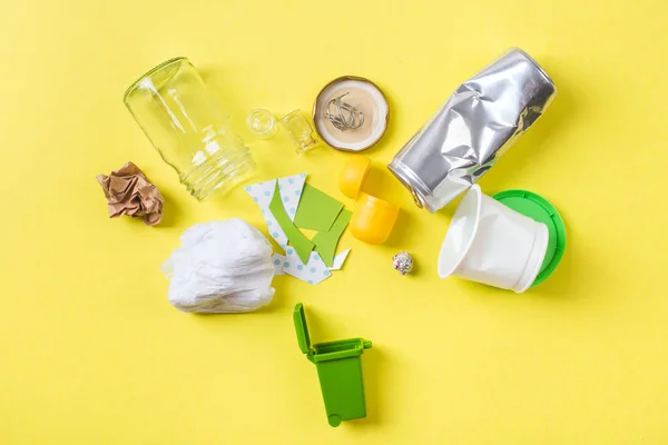 Limpie la basura para reciclar en un recipiente pequeño de metal, papel plástico y vidrio. Concepto de reciclaje en amarillo. Imagen De Stock
