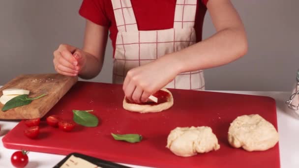 Kochen handgemachte Lebensmittel Konzept. Nahaufnahme von Kind bestreut Pizza Zutat in der heimischen Küche. — Stockvideo