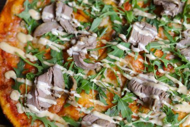 Ahşap bir masada, mantarlı pizza ahşap bir masada, pizza düz bir tabakta keten peçetenin üzerinde. Bir takım cihazlar. Otlu mantarlar telaffuz edilir..