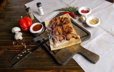 Koyu bir tezgahın üzerinde, açık keten bir peçete, bir kesme tahtası üzerinde dört bıldırcın kızarttı kırmızı soğan halkalarıyla birlikte pita ekmeğinde, keten peçetede, kırmızı biber, biberiye dalında.