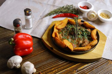 Kızartma tavasında, kızarmış patates dilimleri sos, çatal bıçak takımı, kırmızı dolma biber, şampiyonlar, sos, acı biber, baharatlar, biberiye dalı masada..