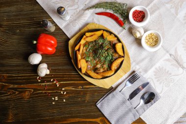 Kızartma tavasında, kızarmış patates dilimleri sos, çatal bıçak takımı, kırmızı dolma biber, şampiyonlar, sos, acı biber, baharatlar, biberiye dalı masada..