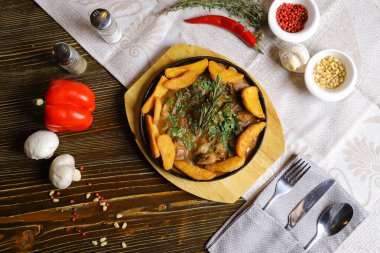 Kızartma tavasında, kızarmış patates dilimleri sos, çatal bıçak takımı, kırmızı dolma biber, şampiyonlar, sos, acı biber, baharatlar, biberiye dalı masada..