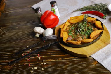 Kızartma tavasında, kızarmış patates dilimleri sos, çatal bıçak takımı, kırmızı dolma biber, şampiyonlar, sos, acı biber, baharatlar, biberiye dalı masada..