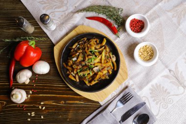 Kızartma tavasında, sosta, çatal bıçakta, kırmızı biberde, şampiyonlarda, sosta, acı biberde, baharatlarda, biberiyede pişirilmiş et parçaları masada. Kızarmış patates kızartma tavasında servis edilir.