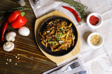 Kızartma tavasında, sosta, çatal bıçakta, kırmızı biberde, şampiyonlarda, sosta, acı biberde, baharatlarda, biberiyede pişirilmiş et parçaları masada. Kızarmış patates kızartma tavasında servis edilir.