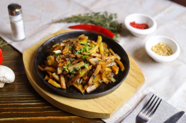 Kızartma tavasında, sosta, çatal bıçakta, kırmızı biberde, şampiyonlarda, sosta, acı biberde, baharatlarda, biberiyede pişirilmiş et parçaları masada. Kızarmış patates kızartma tavasında servis edilir.