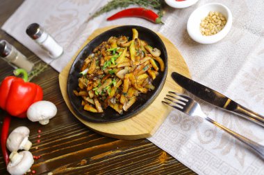 Kızartma tavasında, sosta, çatal bıçakta, kırmızı biberde, şampiyonlarda, sosta, acı biberde, baharatlarda, biberiyede pişirilmiş et parçaları masada. Kızarmış patates kızartma tavasında servis edilir.