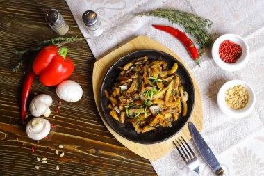 Kızartma tavasında, sosta, çatal bıçakta, kırmızı biberde, şampiyonlarda, sosta, acı biberde, baharatlarda, biberiyede pişirilmiş et parçaları masada. Kızarmış patates kızartma tavasında servis edilir.