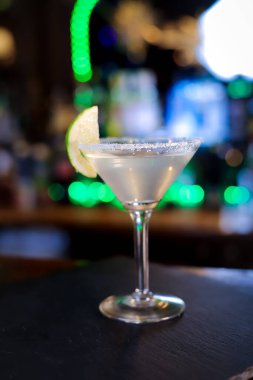 Uzun saplı huni şeklindeki bir camda, alkollü kokteyl opak, opak, bir dilim kireç ve şekerli camın kenarındadır.. 