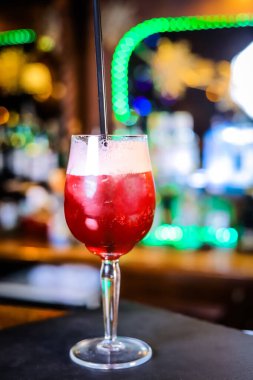 Uzun bir bardakta, opak, üzerinde beyaz köpük ve siyah bir pipet olan kan kırmızısı bir kokteyl.. 
