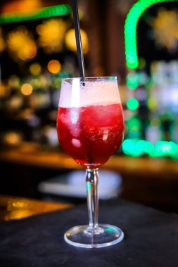 Uzun bir bardakta, opak, üzerinde beyaz köpük ve siyah bir pipet olan kan kırmızısı bir kokteyl.. 
