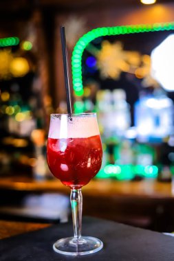 Uzun bir bardakta, opak, üzerinde beyaz köpük ve siyah bir pipet olan kan kırmızısı bir kokteyl.. 