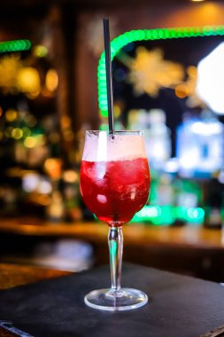 Uzun bir bardakta, opak, üzerinde beyaz köpük ve siyah bir pipet olan kan kırmızısı bir kokteyl.. 
