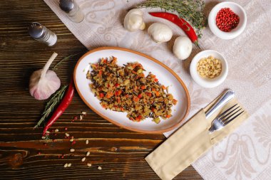 Koyu bir tezgahta Pilaf oval bir tabakta, siyah pirinçli pilav, keten tohumu salatası, çatal bıçak, tuz ve biber, baharat ile servis edilir.