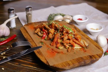 Acı soslu ve baharatlı deniz ürünleri mürekkep balığı. Koyu bir masanın üstünde, çatal bıçak takımı, bir baş sarımsak, beyaz şampiyon, bir çift biber ve tuz, bir biberiye dalı..