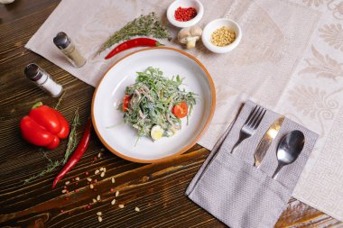 Roka yapraklı salata, haşlanmış dil soslu uzun dilimler halinde kesilmiş. Bir çift tuz ve biber, çatal bıçak takımı, kırmızı biber masayı süsleyin..
