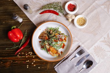 Midyeli salata, roka, kırmızı havyar, yuvarlak tabakta karides çatal bıçak takımı, biber-tuz buharı, bütün kırmızı biber, acı biber, süs olarak baharat. Koyu ahşap bir masanın üzerindeki keten peçete..