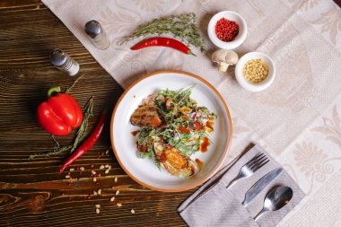 Midyeli salata, roka, kırmızı havyar, yuvarlak tabakta karides çatal bıçak takımı, biber-tuz buharı, bütün kırmızı biber, acı biber, süs olarak baharat. Koyu ahşap bir masanın üzerindeki keten peçete..