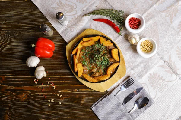 Kızartma tavasında, kızarmış patates dilimleri sos, çatal bıçak takımı, kırmızı dolma biber, şampiyonlar, sos, acı biber, baharatlar, biberiye dalı masada..