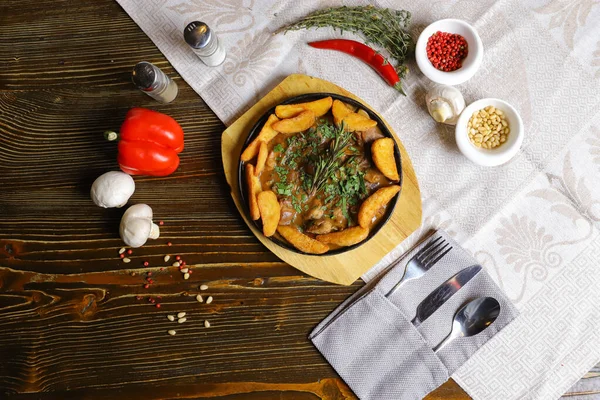 Kızartma tavasında, kızarmış patates dilimleri sos, çatal bıçak takımı, kırmızı dolma biber, şampiyonlar, sos, acı biber, baharatlar, biberiye dalı masada..