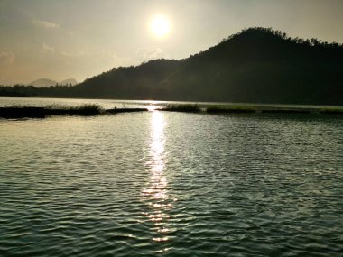 Bulutların ve dağların üzerindeki güzel panoramik manzara. Ortasında güneş yükseliyor.