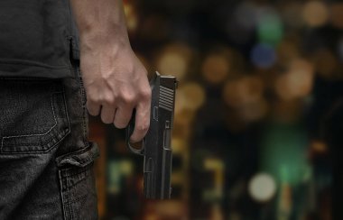 Arka planda erkek el silahı var. Gece lambası bokeh şehirde.