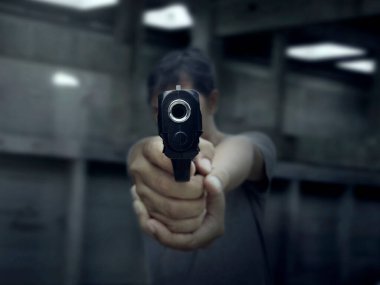 Adam karanlık arka planda hedefe silah doğrultuyor.