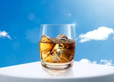 Beyaz masa ve gökyüzü arka planında bir bardak viski.