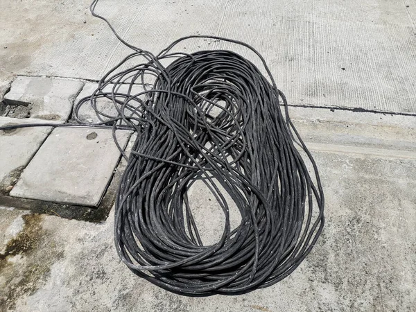 Black rolled electric cable on a road surface background