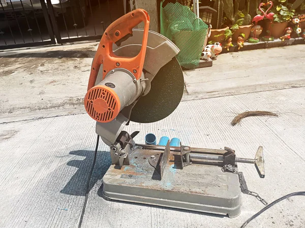 Old rusty sawing machine on the concrete floor at the house under construction. Electrical machinery for cutting hard materials
