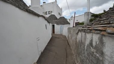 Alberobello, Puglia, İtalya. Ağustos 2021. Büyüleyici tarihi köyde inanılmaz görüntüler var. Konik taştan çatısı olan küçük beyaz trulli 'ye doğru ilerleyen bir ara sokağı araştırıyoruz..